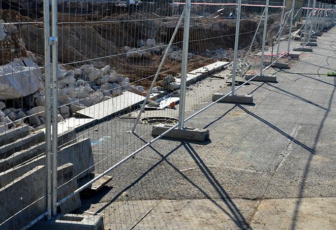 a construction worker installing temporary fence panels for safety and security